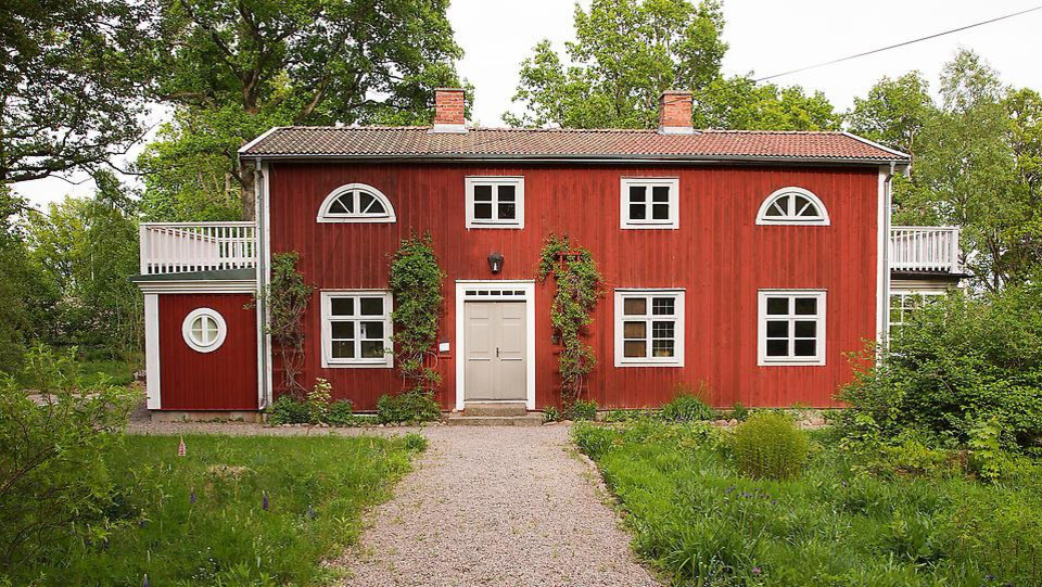 Rött lantligt hus med en grusgång.